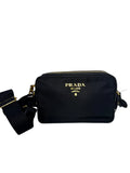 Black Prada handbag with gold accents on a light gray background